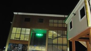 A building with a prominent green exit sign, large windows, and a visible poster on the lower left side.