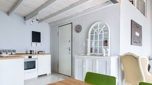 Une cuisine avec des meubles blancs, un plan de travail en bois, une chaise verte et une porte blanche.