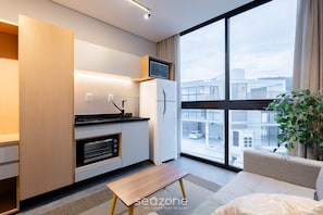 Una cocina moderna con horno empotrado, microondas y un pequeño comedor con banco.