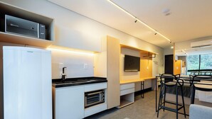 Une cuisine moderne équipée d’un four encastré, d’un réfrigérateur et d’un four à micro-ondes. Un coin repas avec une table et des chaises est également disponible.