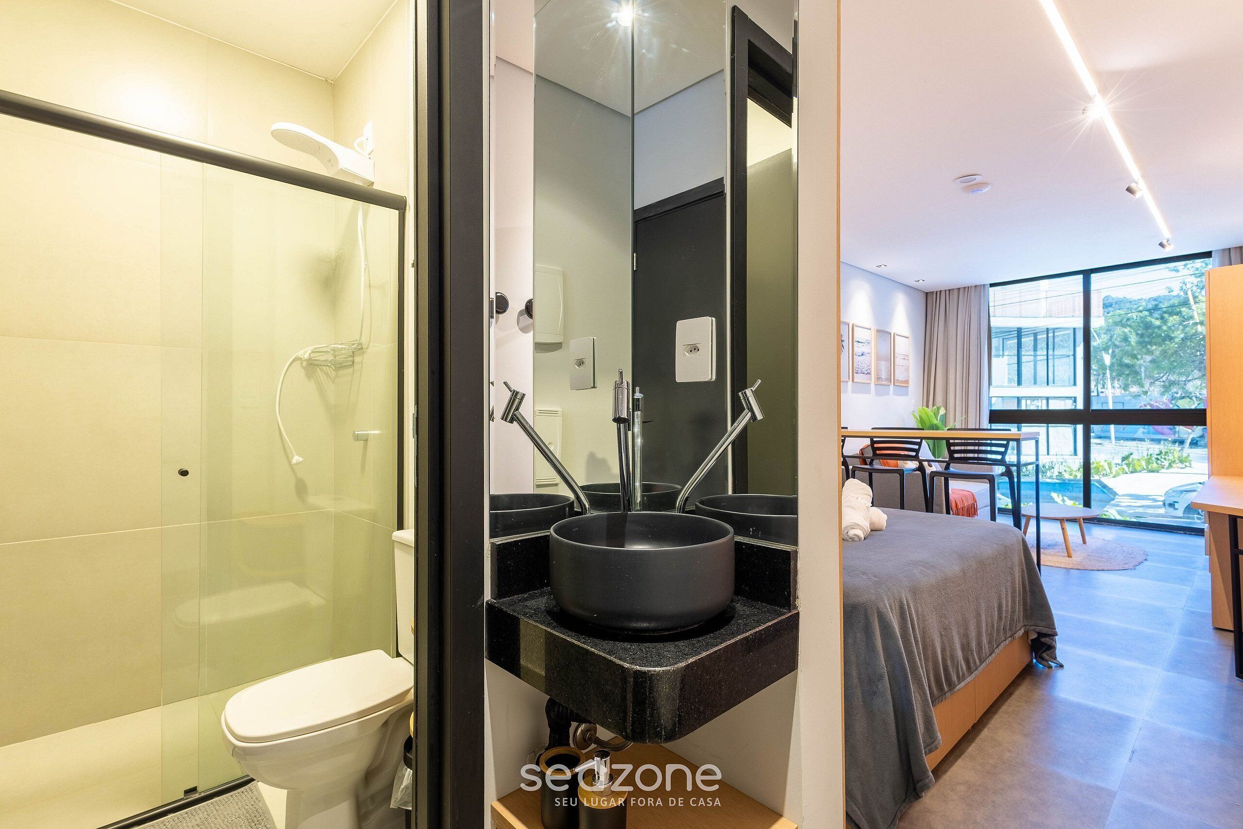 A modern bathroom with a glass-enclosed shower, a black sink, and a toilet.