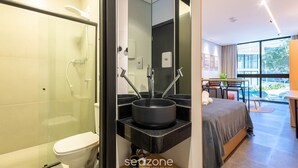 Un baño moderno con ducha de vidrio, lavamanos negro y un inodoro.