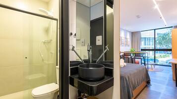 A modern bathroom with a glass-enclosed shower, a black sink, and a toilet.