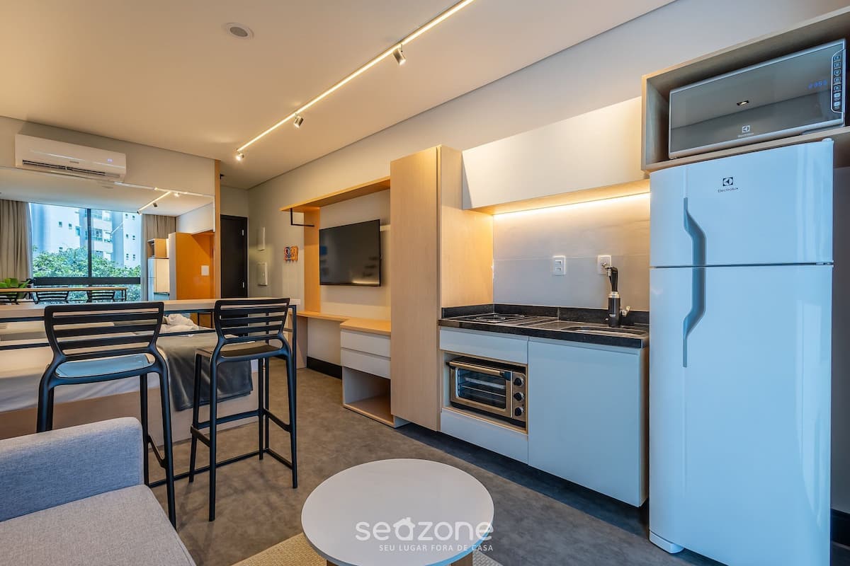A modern kitchen with a built-in oven, a refrigerator, and a dining area with chairs and a table.