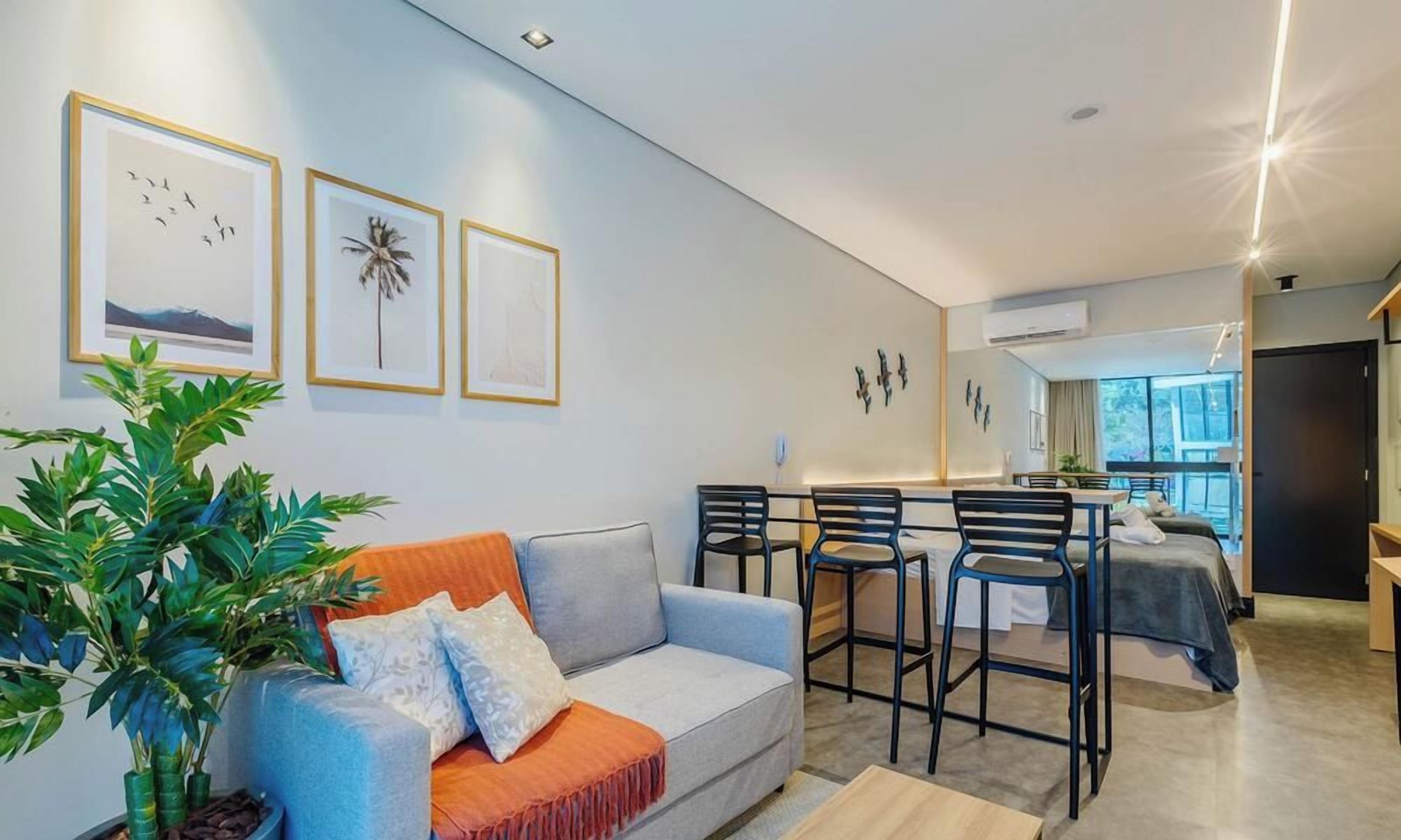 A modern living room with a sofa, a dining table with chairs, and a large plant.