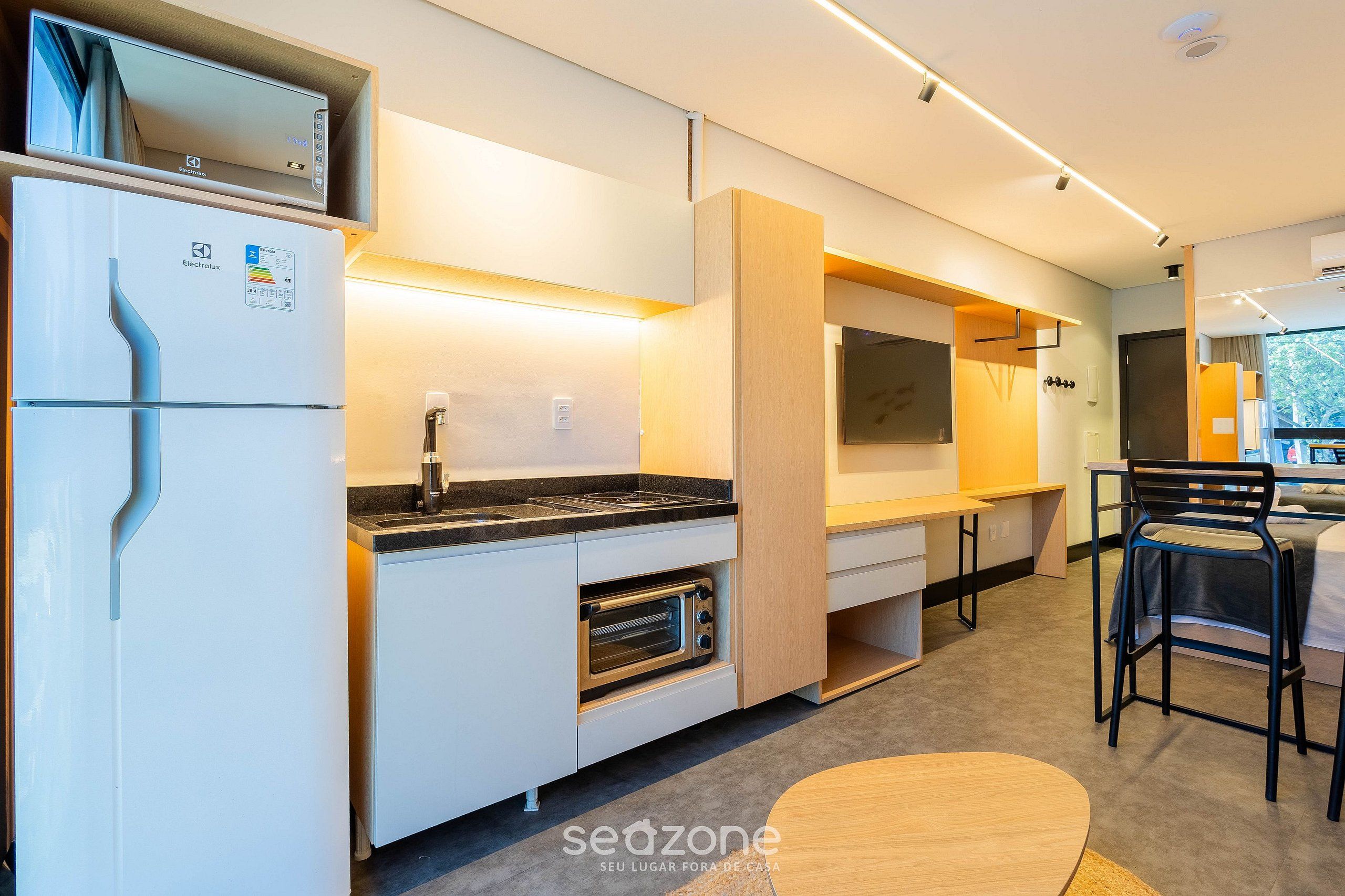 A compact kitchenette with a refrigerator, oven, and microwave.