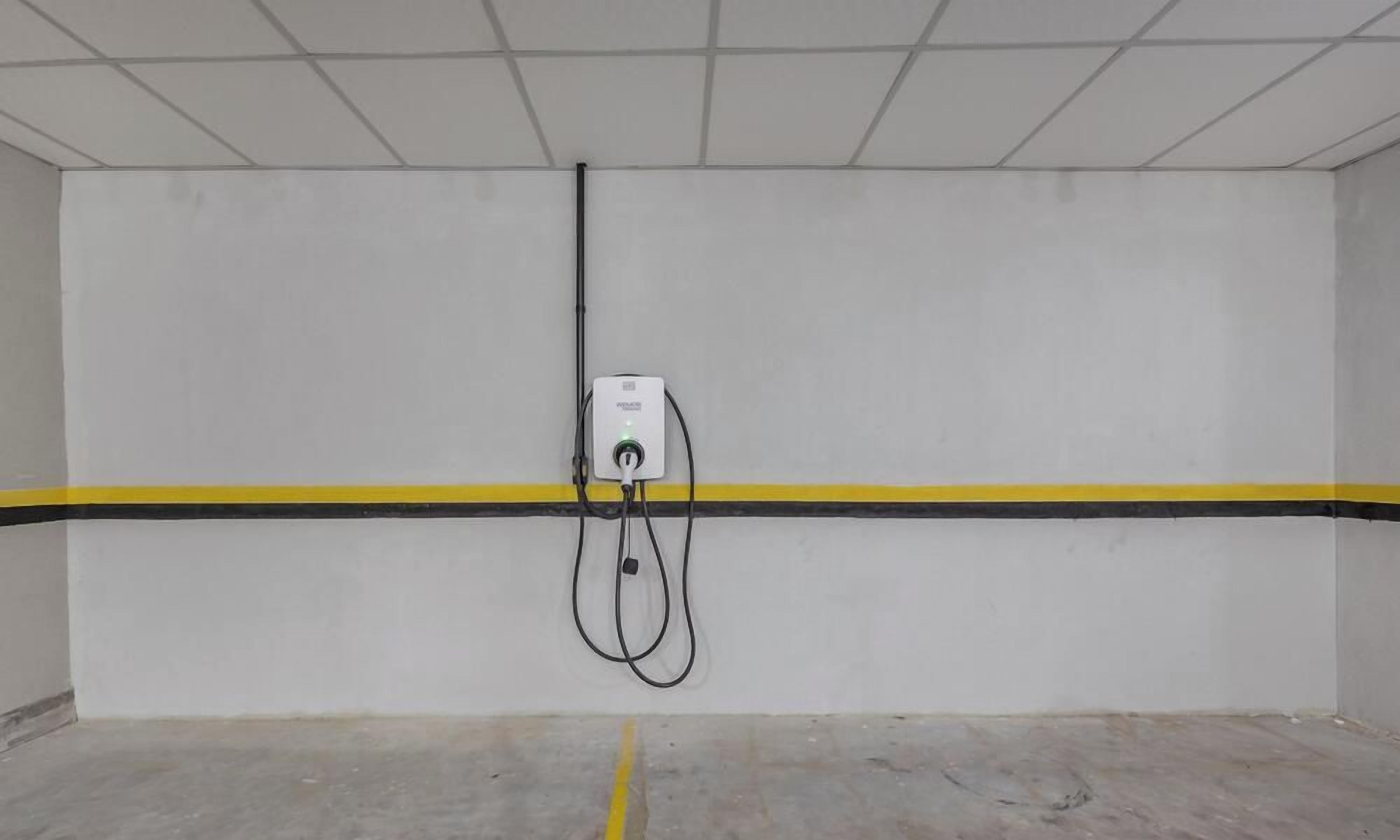Une pièce propre et vide, avec un mur blanc, une bande jaune et une prise électrique avec un câble.