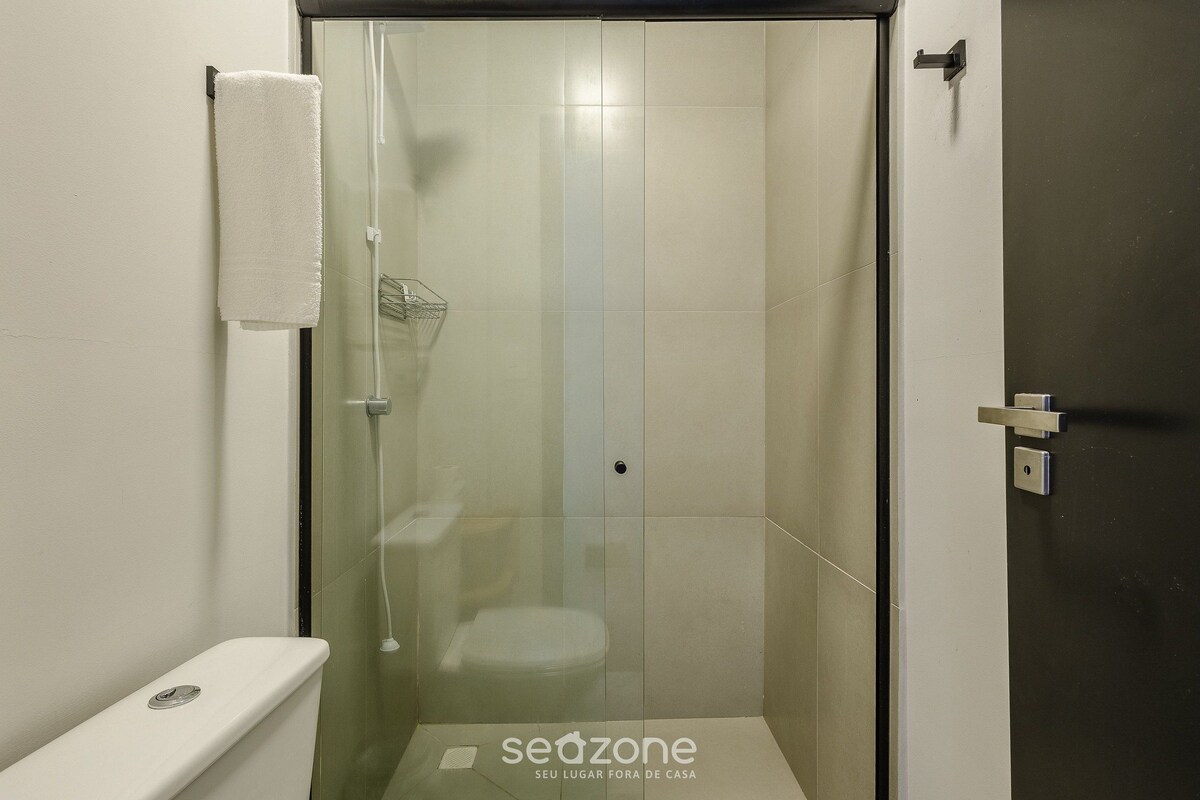 A modern bathroom with a glass-enclosed shower, a toilet, and a towel rack.