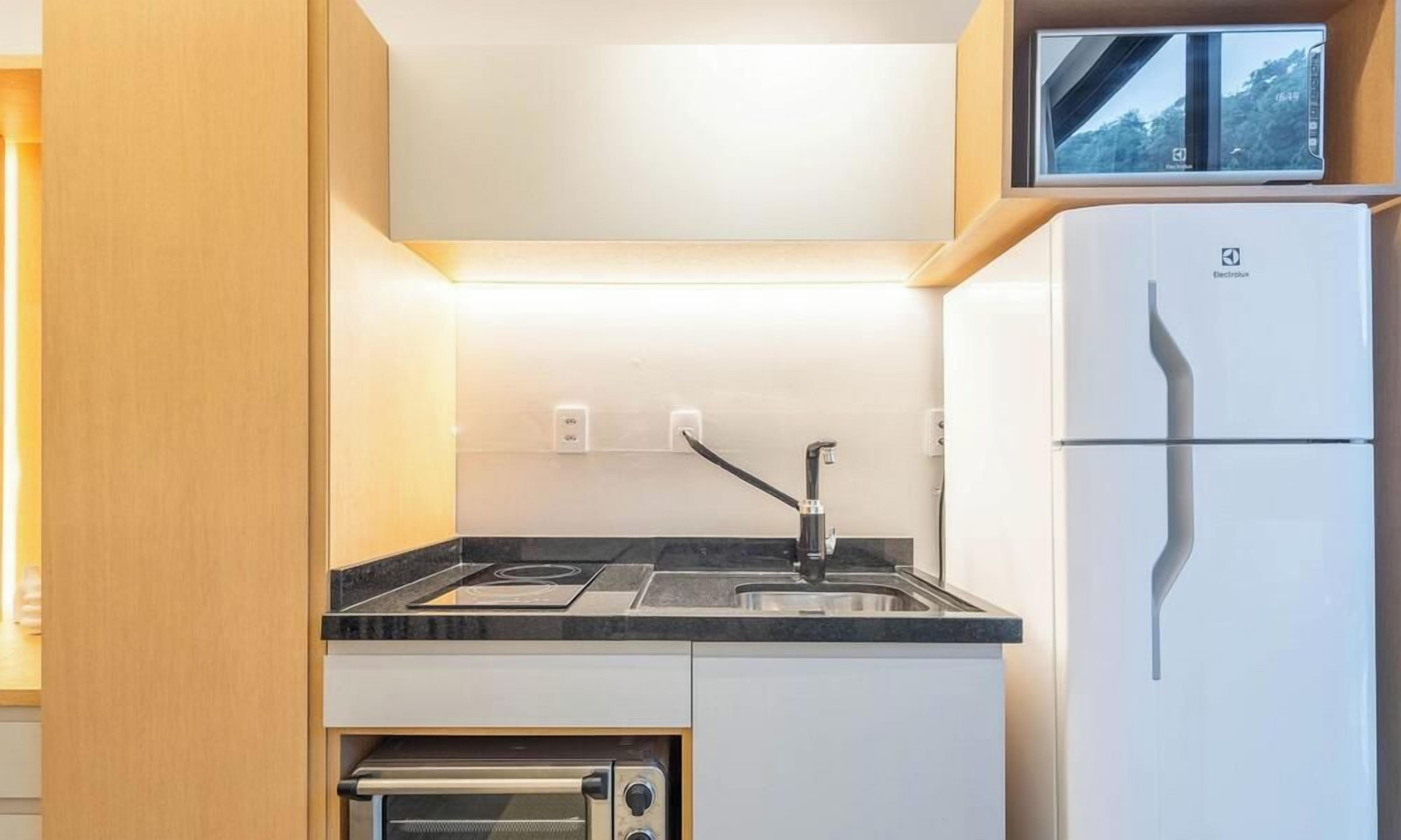 A compact kitchen with a built-in oven, a sink, and a refrigerator.
