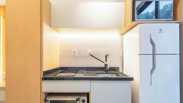 A compact kitchen with a built-in oven, a sink, and a refrigerator.