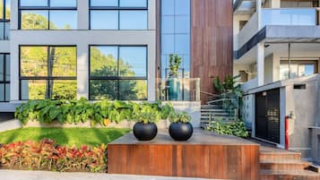 Un edificio moderno con amplios ventanales, una terraza de madera y un letrero que dice "BRAVA STUDIOS".