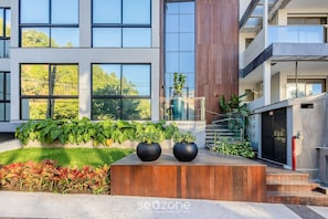Un edificio moderno con amplios ventanales, una terraza de madera y un letrero que dice "BRAVA STUDIOS".