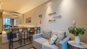 Un espace de vie moderne comprenant un canapé, une petite table et un coin bar avec des tabourets.