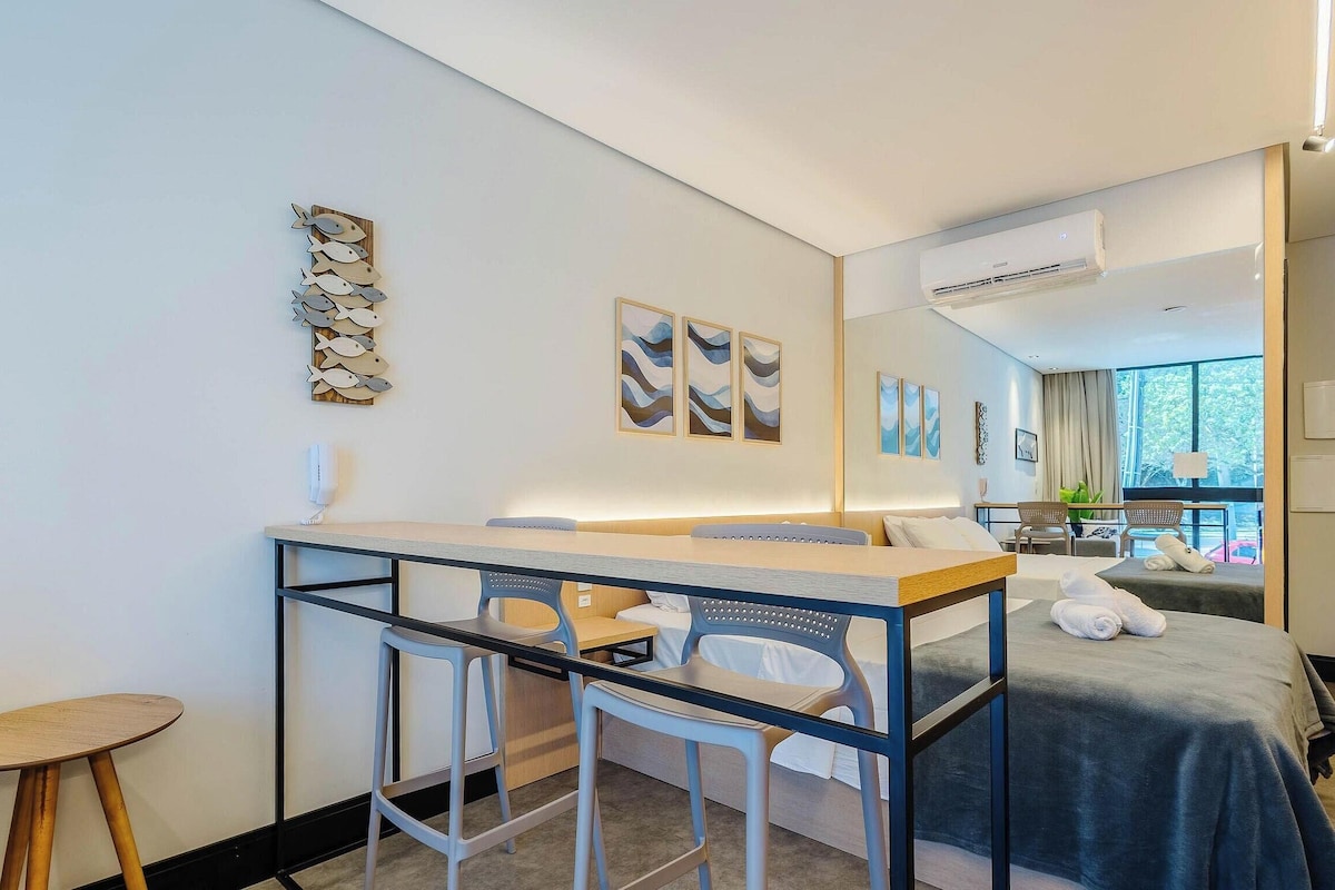 Una habitación de hotel moderna con una cama, un escritorio con sillas y obras de arte en las paredes.