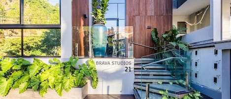 A modern building with a staircase, large windows, and potted plants.