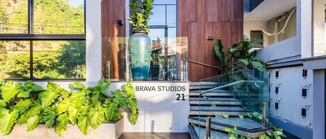A modern building with a staircase, large windows, and potted plants.