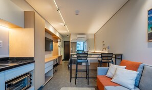 A modern kitchen with a built-in oven and a dining area with a table and chairs. - Sua estadia próxima da Praia Brava - BSO (Balneário Camboriú)