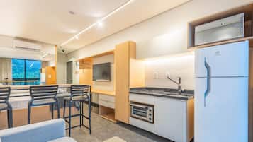 A compact kitchen with a built-in oven, a refrigerator, and a dining area with a table and chairs.