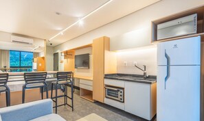 A compact kitchen with a built-in oven, a refrigerator, and a dining area with a table and chairs.