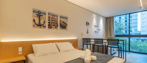A modern hotel room with a large bed, a desk, and a balcony with chairs.