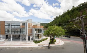 Un bâtiment moderne à plusieurs étages, doté de grandes fenêtres et d’une façade combinant des panneaux de verre et de bois.