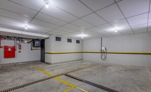A clean, well-lit parking garage with concrete floors, yellow safety lines, and a fire extinguisher on the left. - Sua estadia próxima da Praia Brava - BSO (Balneário Camboriú)