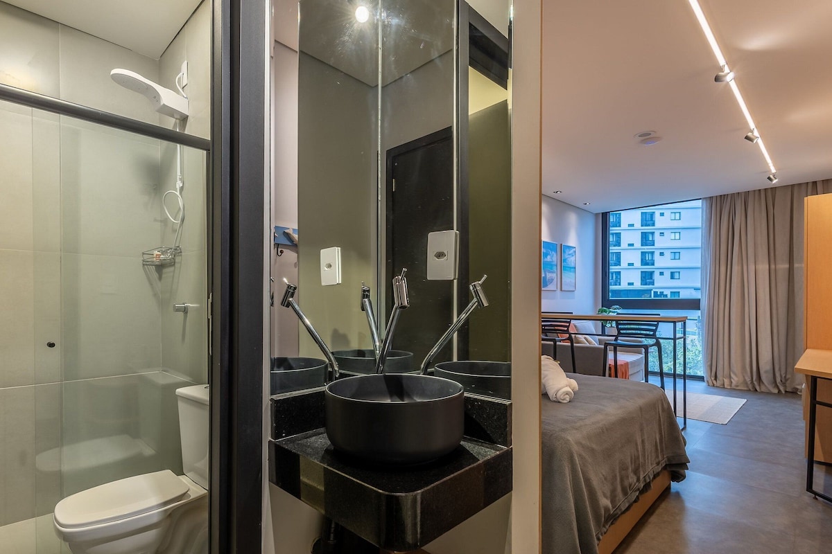 Un baño moderno con cabina de ducha de vidrio, un lavabo negro de gran capacidad y un inodoro.