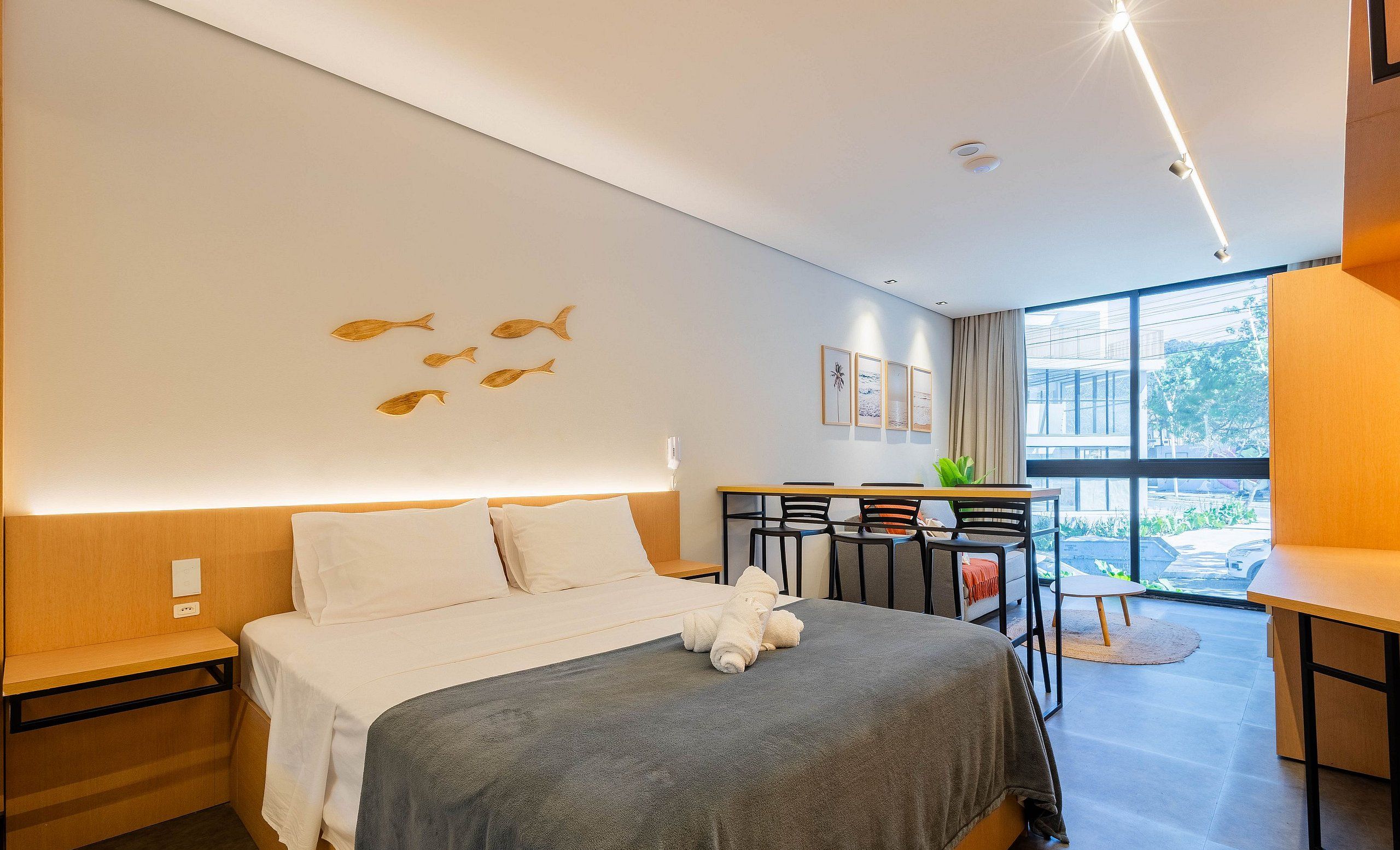 A modern hotel room with a bed, a desk, and a view of the outdoors.
