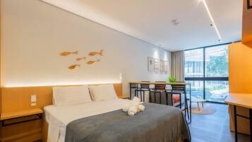 A modern hotel room with a bed, a desk, and a view of the outdoors.