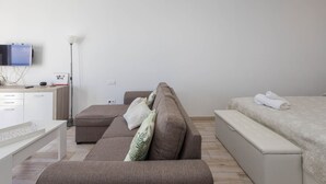 A modern hotel room with a sofa, a bed, a desk, and a flat-screen TV mounted on the wall. - PentHouse Loft - Terrace & Natural Pool (Gáldar)