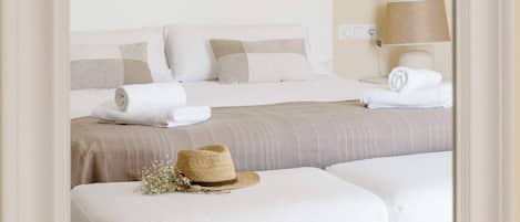 A bedroom with a bed, two white upholstered benches, a lamp, and a mirror.