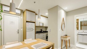Une cuisine moderne avec des meubles blancs, un four encastré et un micro-ondes.
