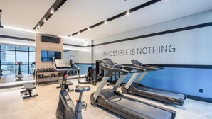 A modern gym with treadmills, dumbbells, and a motivational wall saying "IMPOSIBLE IS NOTHING". - IFT - Ed. Infinity Tower Flat 350m From Meia Praia (Itapema)