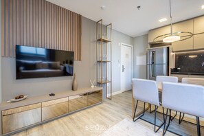 A modern kitchen with a built-in oven, a refrigerator, and a dining area with a table and chairs. - IFT - Ed. Infinity Tower Flat 350m From Meia Praia (Itapema)