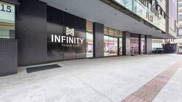 A modern building with a sign reading "INFINITY TOWER FLAT".