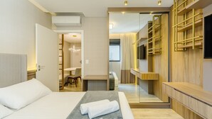 A modern hotel room with a bed, a desk, and a TV mounted on the wall. - IFT - Ed. Infinity Tower Flat 350m From Meia Praia (Itapema)