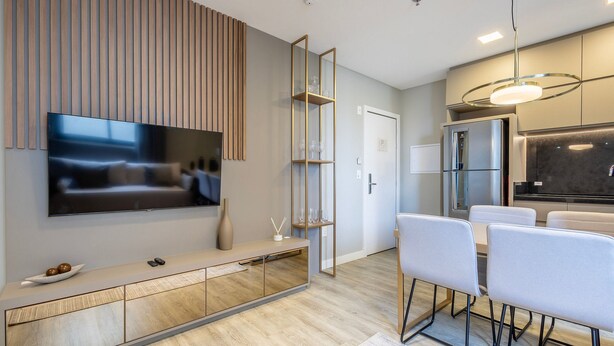 Une cuisine moderne équipée d’un four encastré, d’un réfrigérateur et d’un coin repas avec une table et des chaises.