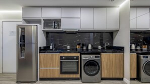 A modern kitchen with stainless steel appliances, a black marble backsplash, and wooden cabinetry. - IFT - Ed. Infinity Tower Flat 350m From Meia Praia (Itapema)