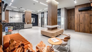 A modern hotel lobby with a reception desk, seating area, and wooden accents. - IFT - Ed. Infinity Tower Flat 350m From Meia Praia (Itapema)