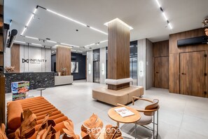A modern hotel lobby with a reception desk, seating area, and wooden accents. - IFT - Ed. Infinity Tower Flat 350m From Meia Praia (Itapema)