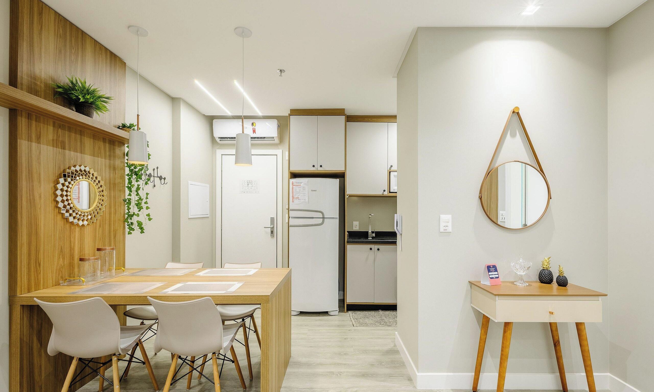 Een moderne keuken met witte kasten, een koelkast en een eethoek met een houten tafel en stoelen.