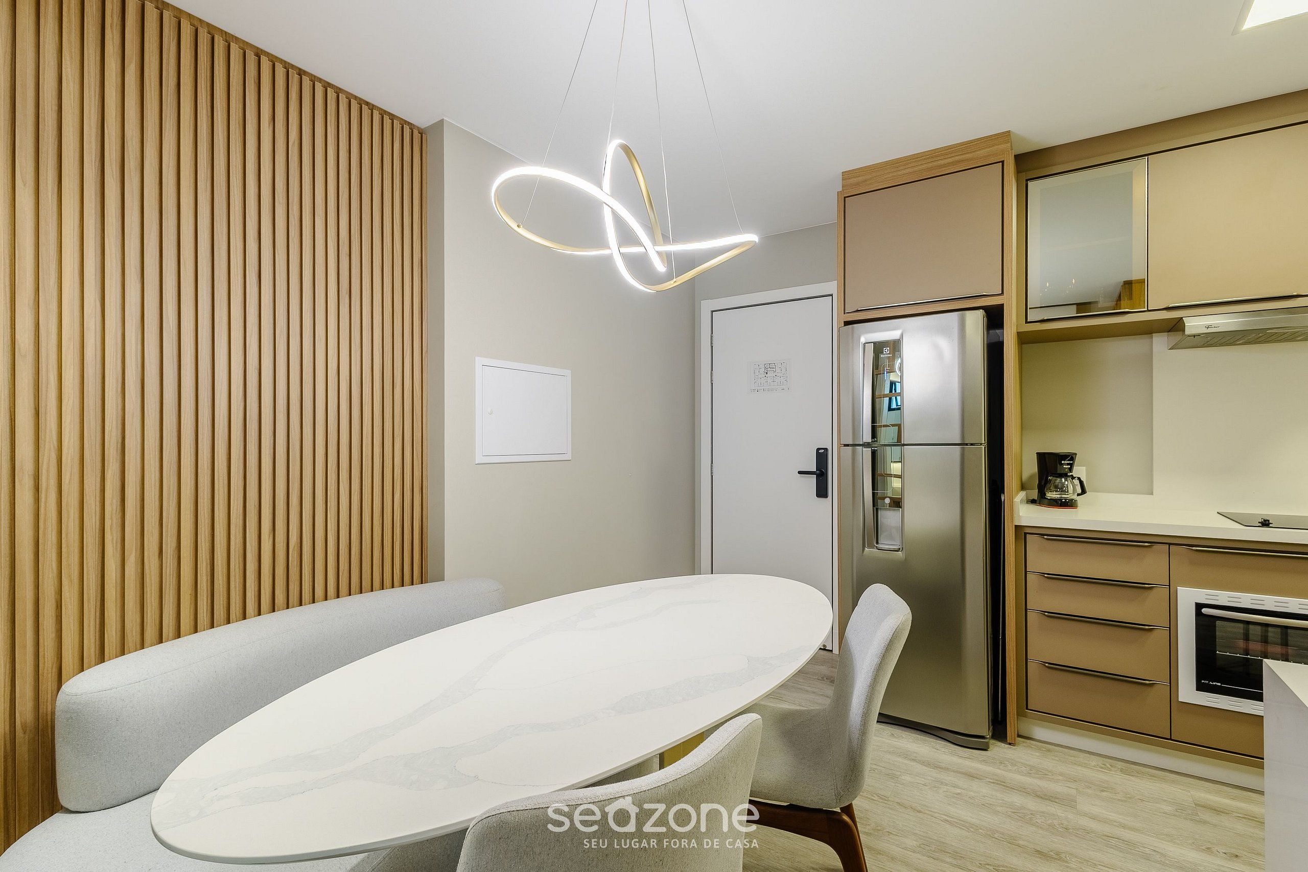 A modern kitchen with a built-in oven, a refrigerator, and a wooden panel wall.
