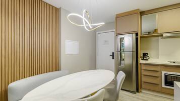 A modern kitchen with a built-in oven, a refrigerator, and a wooden panel wall.