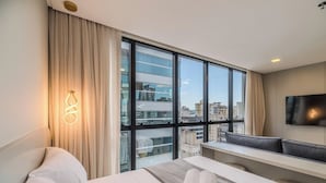 A hotel room with a large window, a bed, a desk, and a TV mounted on the wall. - IFT - Ed. Infinity Tower Flat 350m From Meia Praia (Itapema)