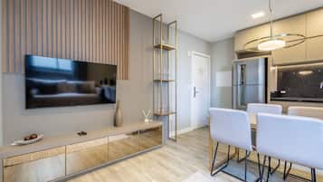 Una cocina moderna con horno empotrado, refrigerador y comedor con mesa y sillas.