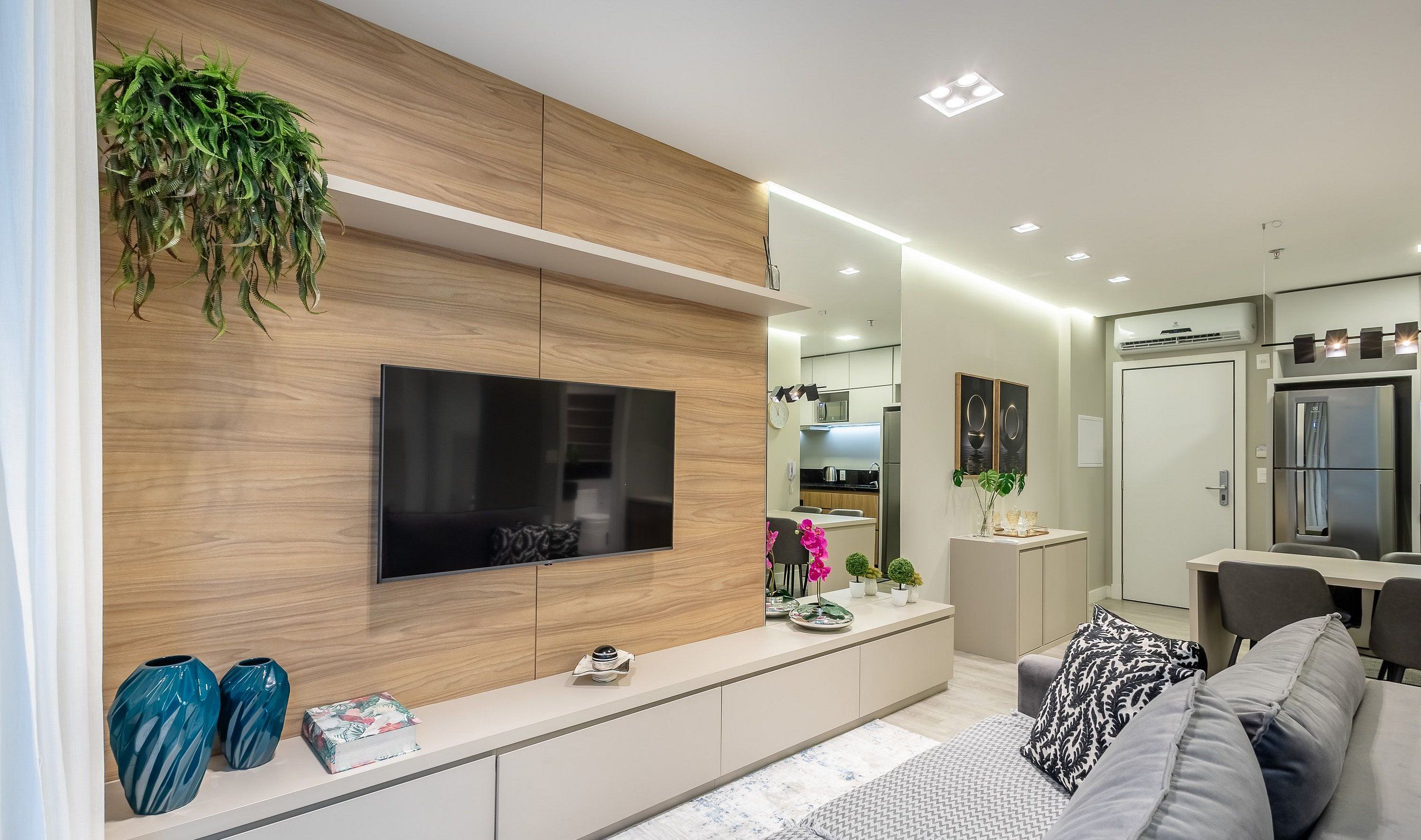 Una sala de estar moderna con televisor de pantalla plana, paneles de madera, una mesa de centro y un sofá.