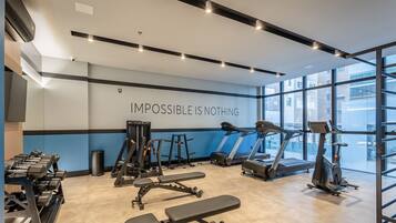 A modern gym with treadmills, weight machines, and dumbbells.