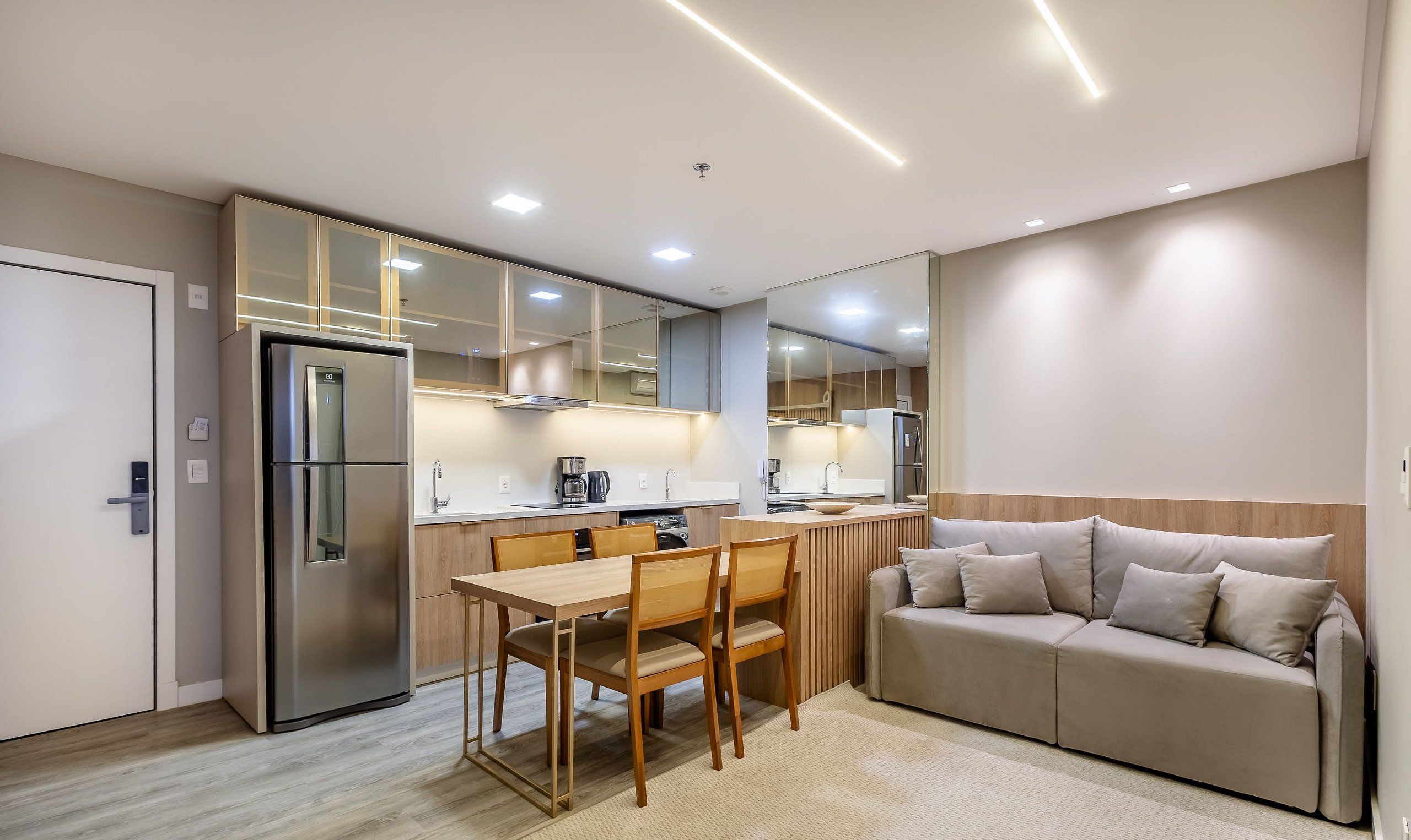 A modern kitchen with a refrigerator, stove, and dining area with a table and chairs.
