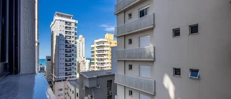 Un palazzo residenziale a più piani con numerosi balconi e una vista aperta sul mare sullo sfondo.