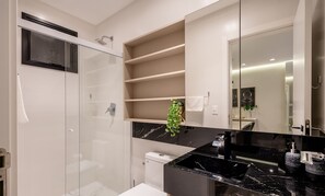 A modern bathroom with a glass shower enclosure, a black marble countertop, and built-in shelves. - IFT - Ed. Infinity Tower Flat 350m From Meia Praia (Itapema)